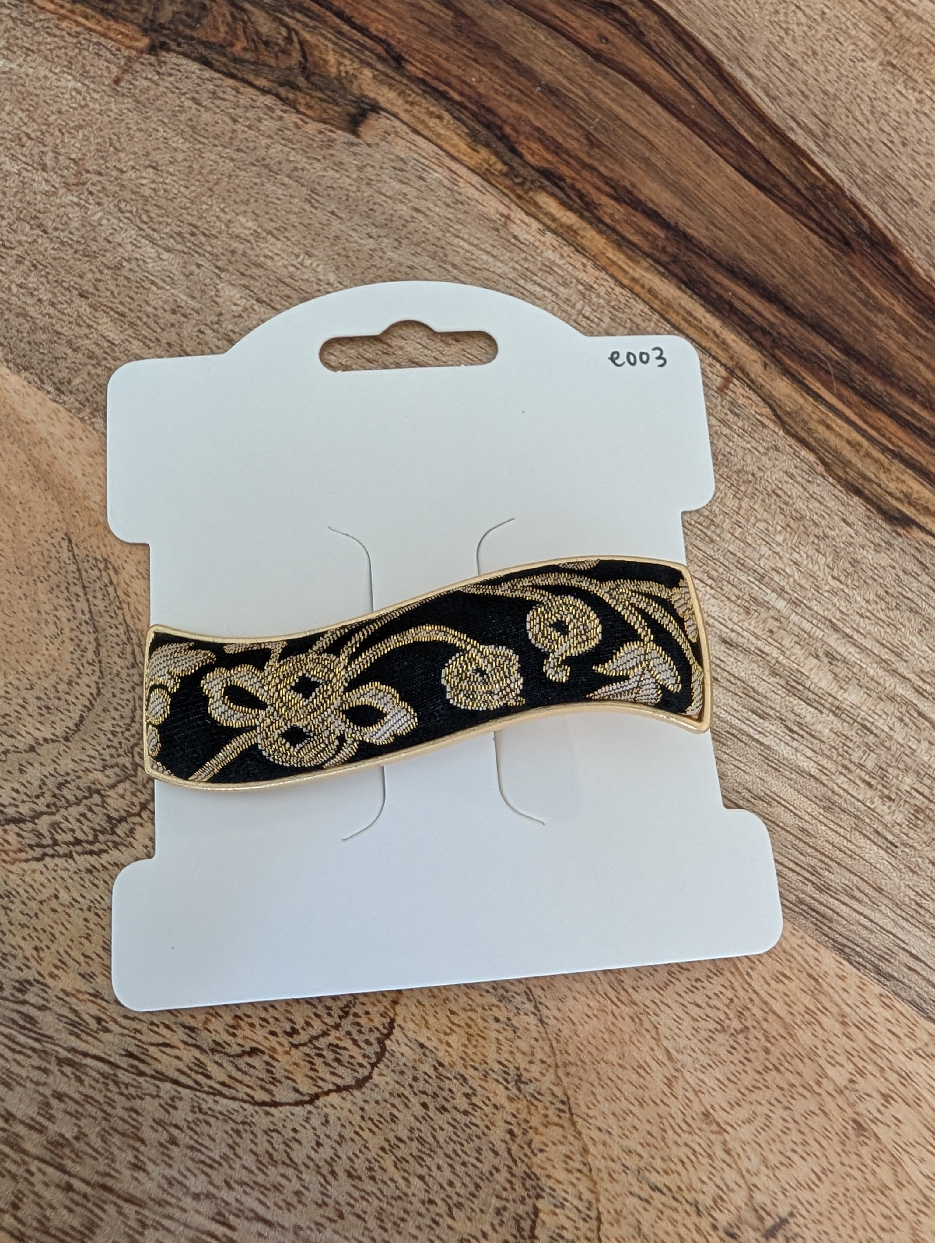 E003 - Black & gold Song Brocade wave barrette on packaging card