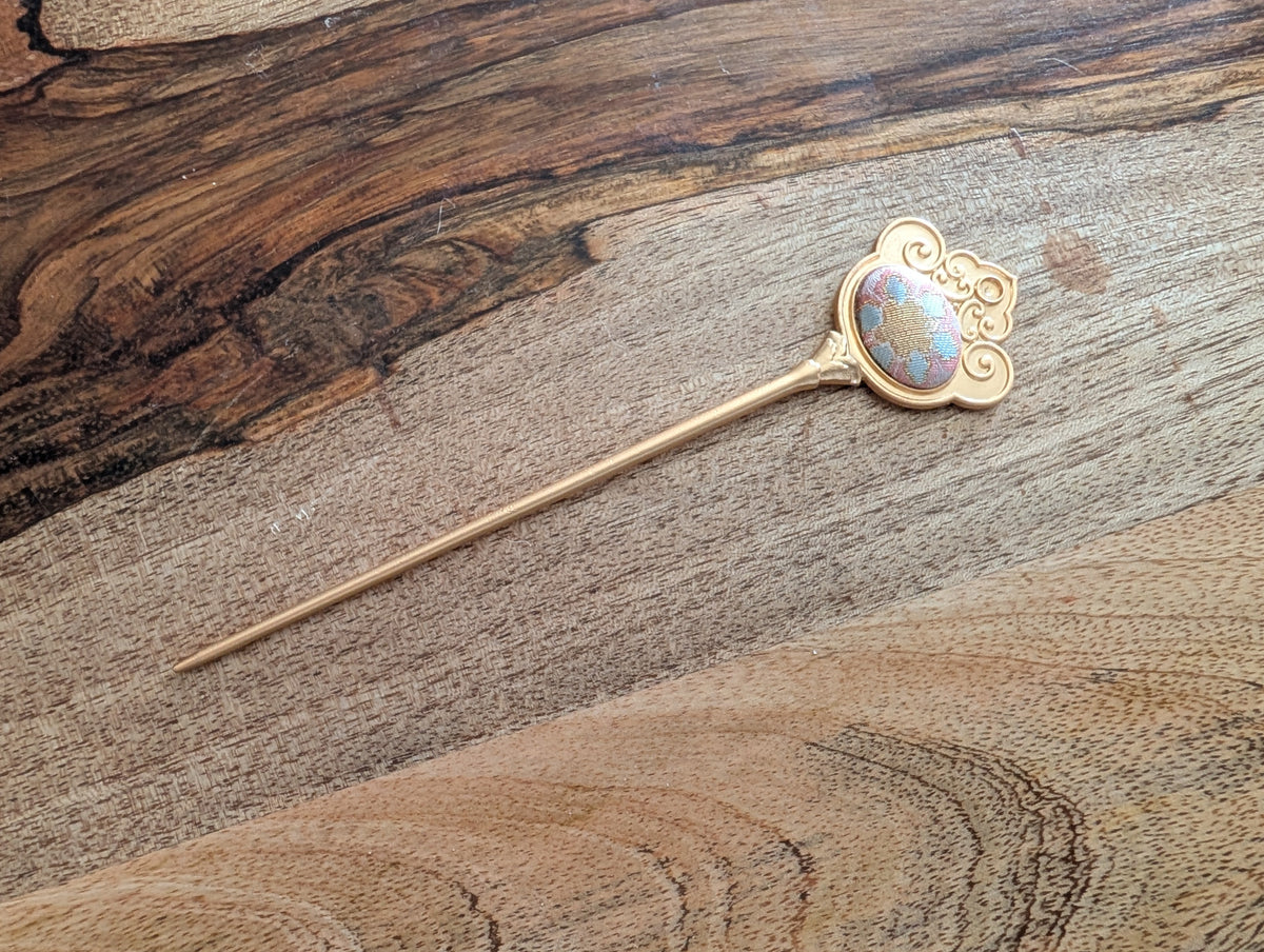 N012 - Song Brocade hair stick pin with gold cloud-scroll frame on wood surface